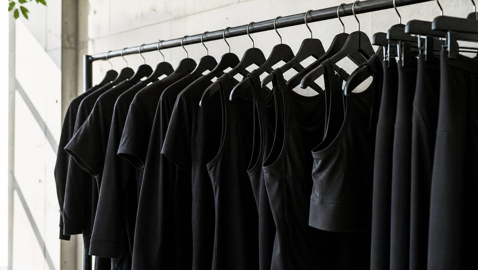 Rack of finished black activewear garments hanging evenly on a rail in a bright clean room