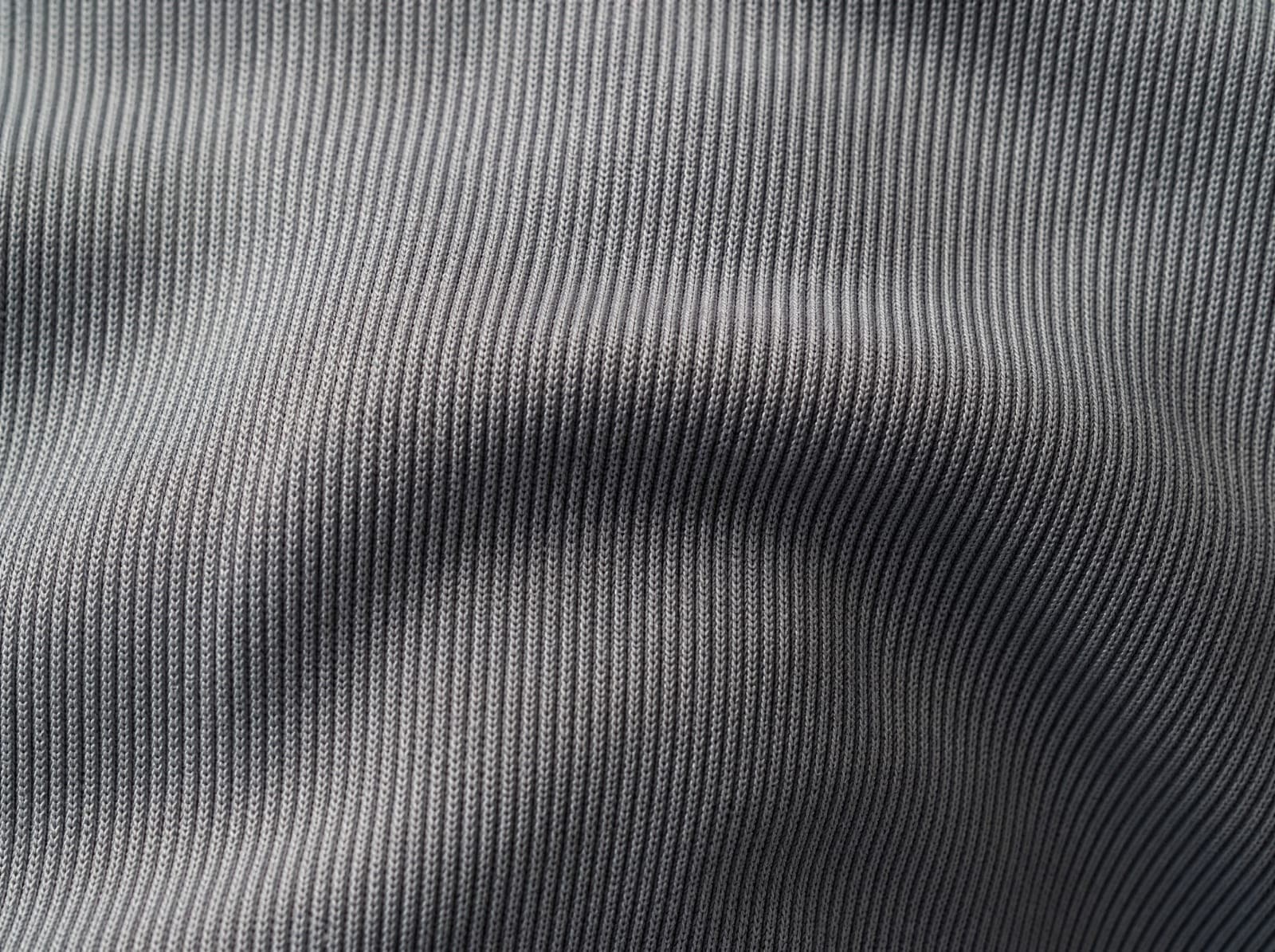 Close-up of grey seamless ribbed nylon knit, fabric slightly stretched to show the weave, filling the whole frame