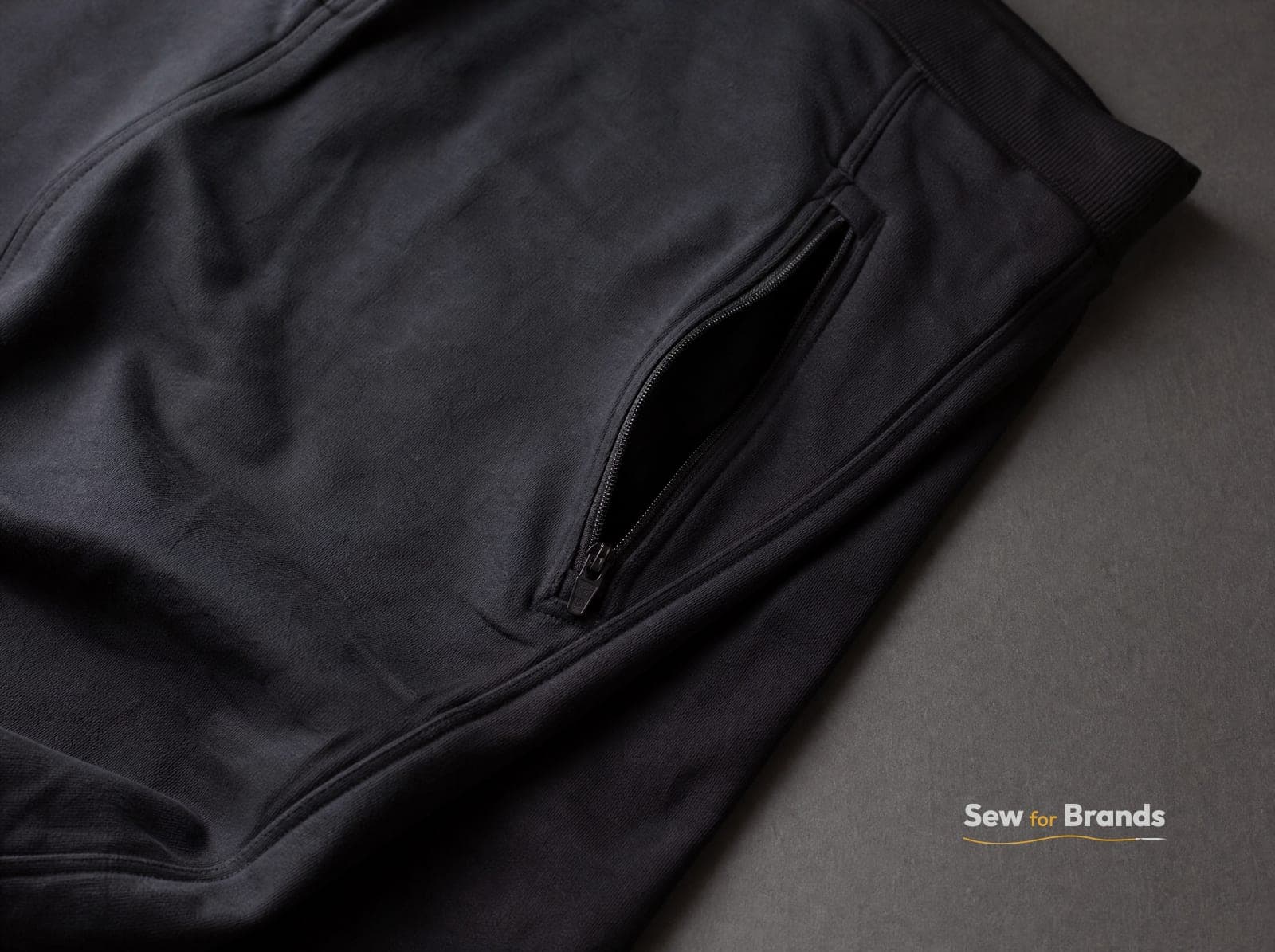 Ribbed ankle cuff and zip pocket of black joggers, close-up