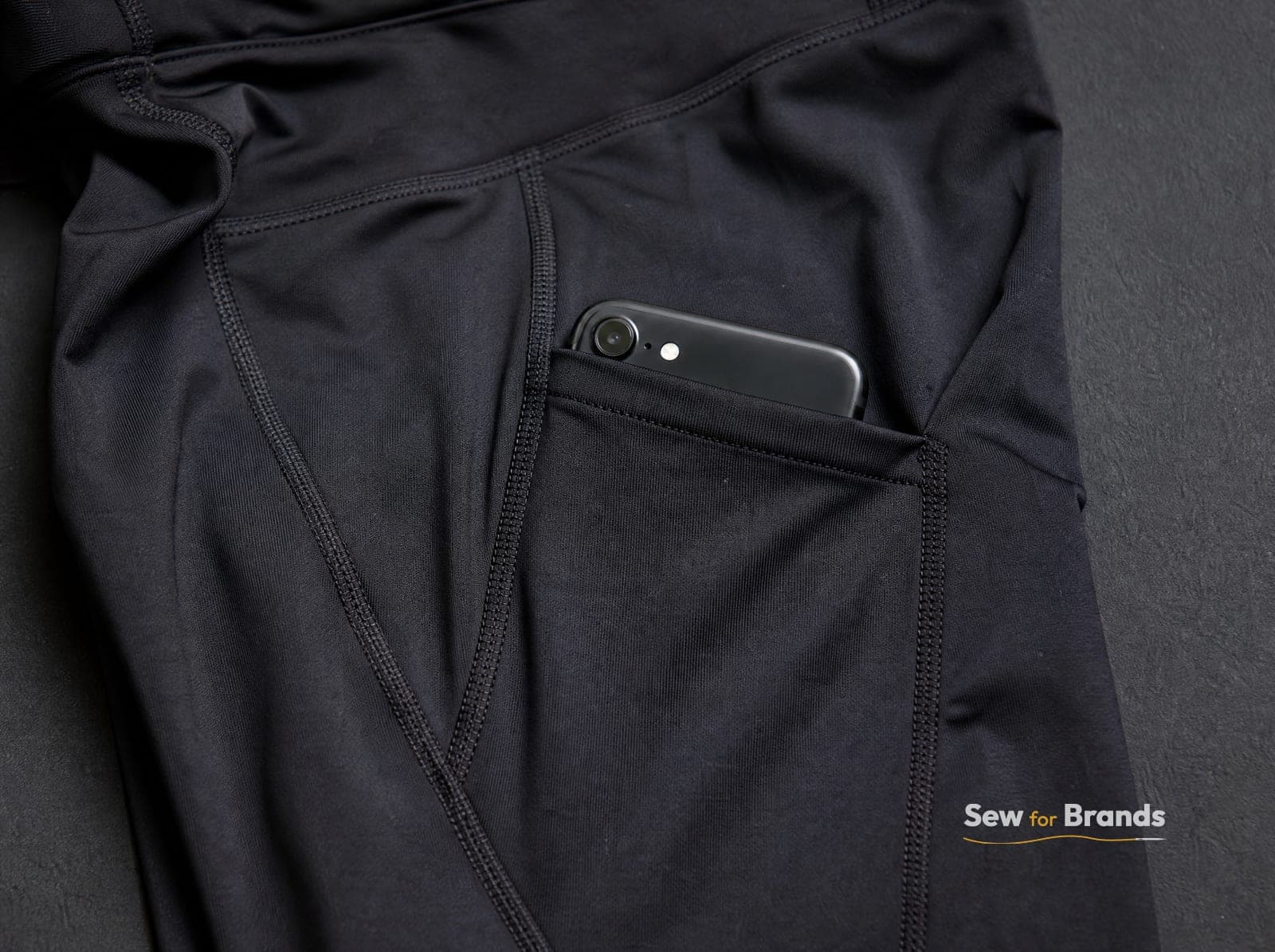 Black leggings with a side phone pocket, pocket slightly open, detail view