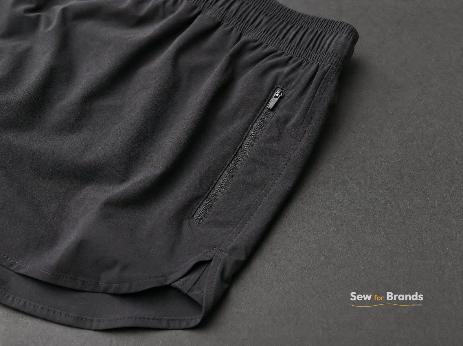 Side seam and small zip pocket of black running shorts, close-up