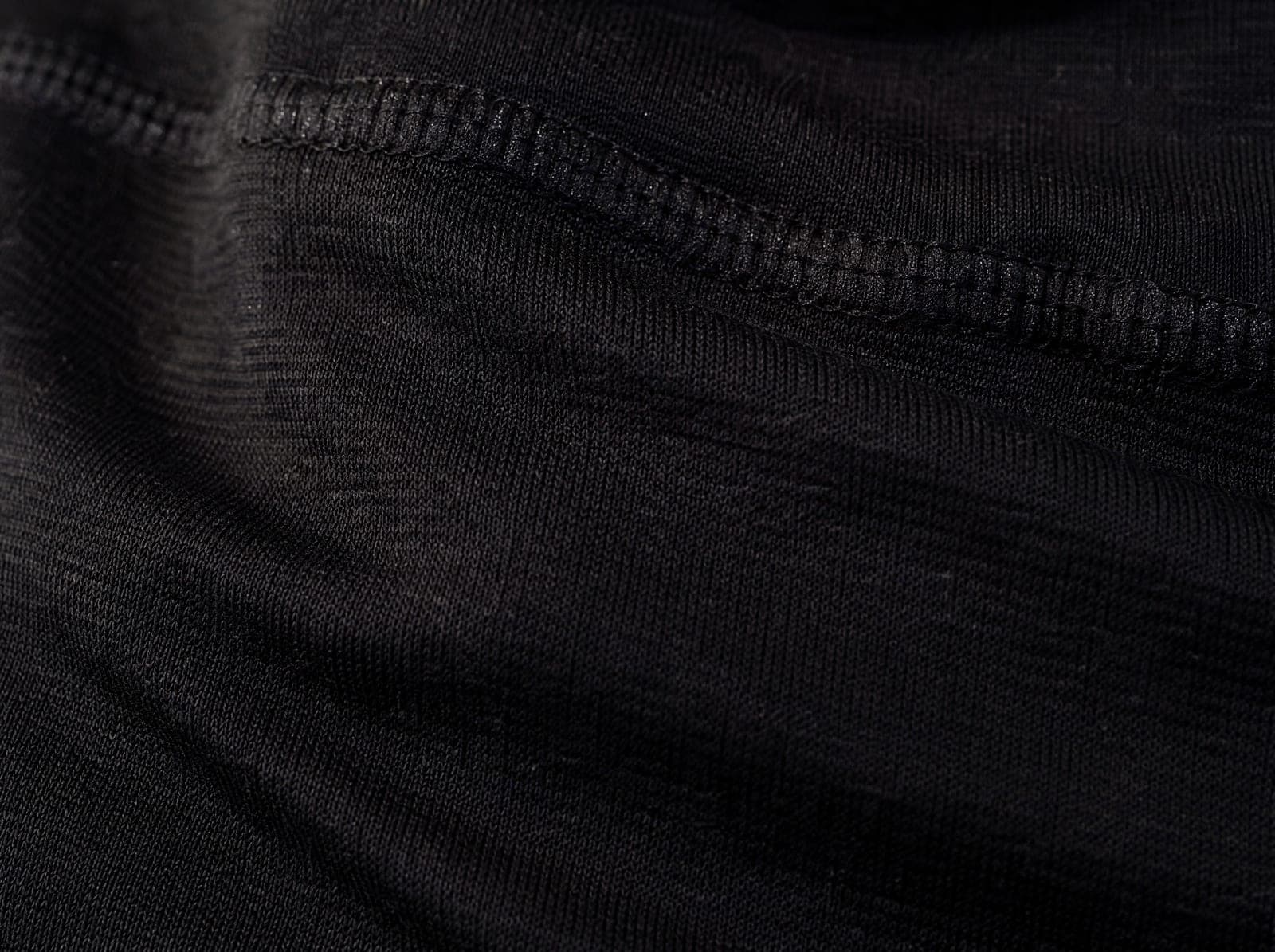 Close-up of black brushed nylon-spandex knit, fabric slightly stretched to show the weave, filling the whole frame