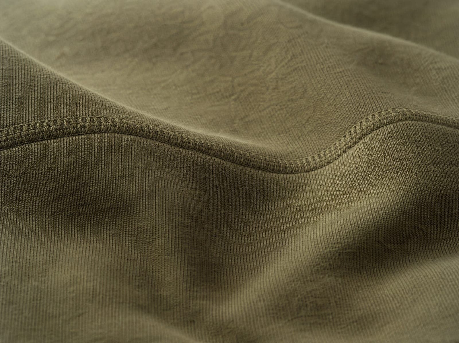 Close-up of olive recycled cotton fleece, fabric slightly stretched to show the weave, filling the whole frame